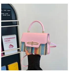 Pink PU leather and multicolor woven handbag with golden buckle held by a model