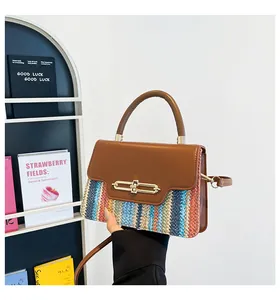 Close-up of color-block straw and leather handbag with gold metal clasp on white shelf