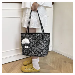 Detail of a large black tote bag featuring geometric patterns and a cloud charm