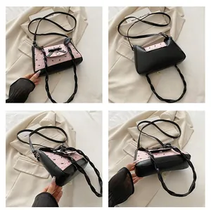 Detail view of pink bow baguette bag with heart pendant and dual woven shoulder straps