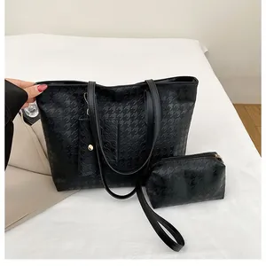 Macro view of textured black houndstooth embossed tote bag set with matching small pouch