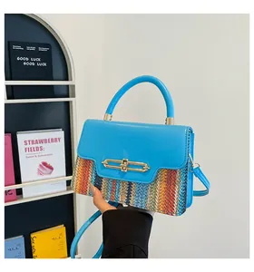 Detail of blue leather flap and woven stripe pattern on crossbody bag with gold lock