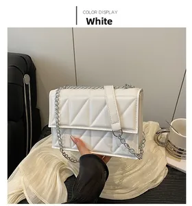 Close-up of white quilted mini square bag with silver chain strap and leather texture