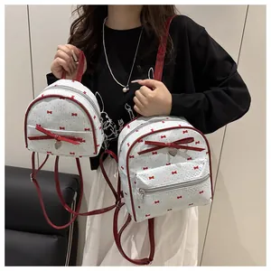 Detailed comparison of white polka dot backpacks in two sizes with red bow accents