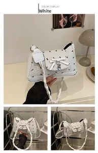 Close-up of white bow shoulder bag featuring black patterns and heart metal pendant