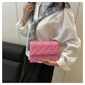 Close-up of bright pink quilted mini crossbody bag with silver chain strap on model