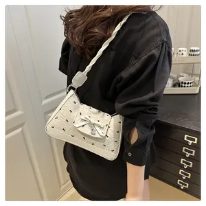 Detail of white bow shoulder bag with heart pendant and black ribbon embroidery