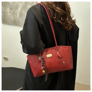 Detail of red vintage underarm bag with matte leather texture and golden brand plate