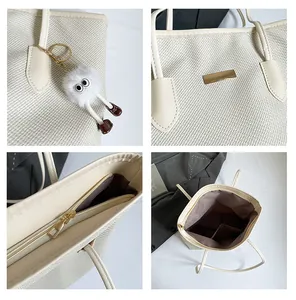 Detail view of beige woven tote bag showing gold zipper, leather straps and fluffy charm