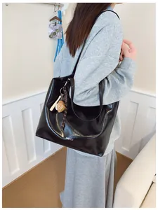 Détail d'un sac cabas noir brillant avec texte Fashion et un accessoire de baseball