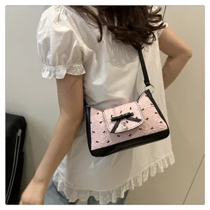 Detail of pink bow handbag with heart charm and black ribbon on a model side-view