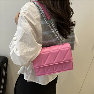 Pink quilted crossbody bag with silver chain strap shown on model in white shirt