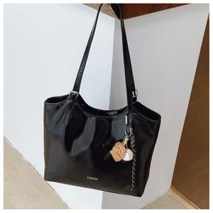 Détail du sac cabas noir en cuir brillant avec texte FASHION et breloque baseball