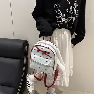 White mini backpack for women with red bow patterns and a heart pendant charm