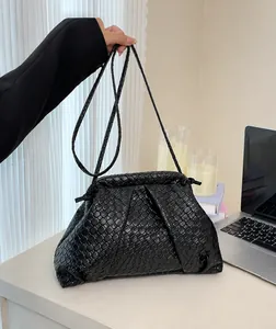 Detail of black woven cloud bag showing texture on a white table with desk accessories