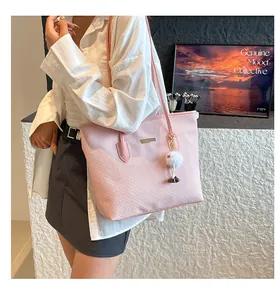 Detail of light pink tote bag with woven texture, golden plate, and cute plush charm