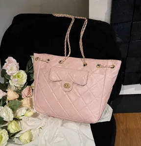 Close-up of pink quilted tote bag showing the gold twist lock and chain strap details