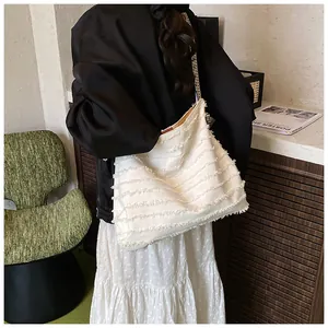 Detail of off-white straw tote with fringe texture and patterned shoulder strap