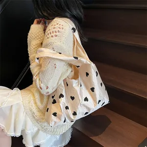 Cream tote bag with black heart patterns held by a woman on wooden stairs