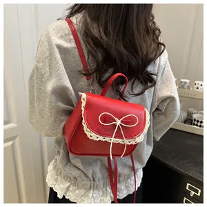 Detail of red leather backpack featuring white lace trim and bow on a model's back