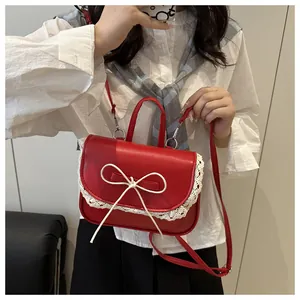 Detail of red PU leather bag with white lace edges and a delicate ribbon bow accent
