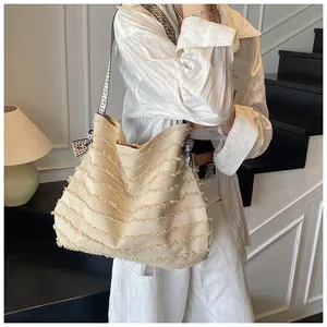 Close-up of beige woven tote bag featuring fringe details and striped bow decoration