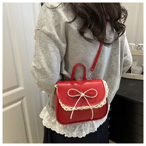 Detail of red PU leather bag with white lace edges and a delicate bow tie on the flap
