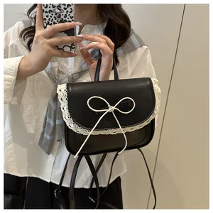 Detail of black PU leather backpack featuring delicate white lace trim and a bow accent