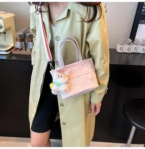 Detail der rosa plissierten Oxford-Eimertasche mit Plüschbär-Anhänger und Webriemen