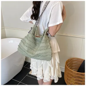 Detail of light green canvas tote with fringe layers and geometric woven shoulder strap