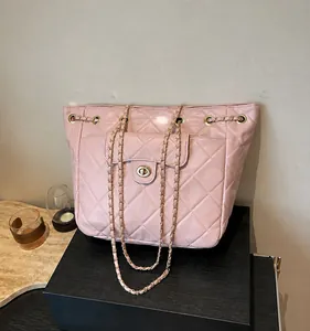 Close-up of pink quilted tote bag showing metal turn-lock pocket and leather chain strap