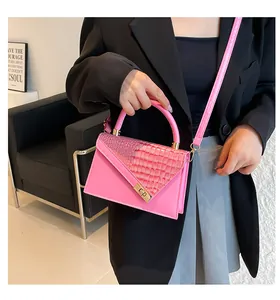 Detailweergave van roze crossbodytas met krokodillenpatroon en gouden draaislot
