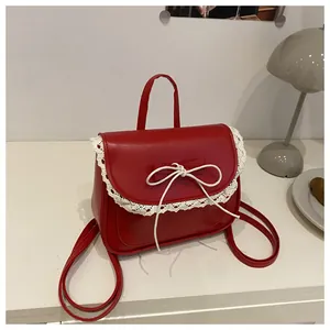 Detailed shot of red leather mini backpack with white lace trim and bow knot detail