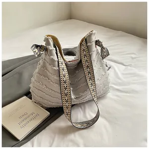 Detail of grey canvas tote bag with fringe textures and geometric ribbon shoulder strap
