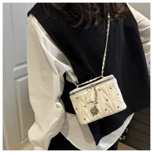 Dettaglio della mini borsa bianca trapuntata con borchie argento e ciondolo rosa