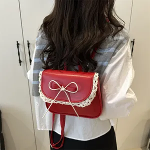 Red leather mini backpack with bow and lace trim shown on a model in a bright setting