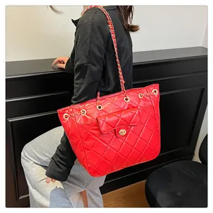 Close-up of red quilted tote with gold chain strap and metal turn-lock on luxury leather