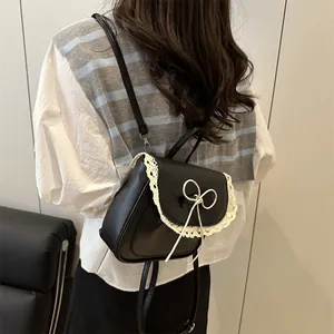 Women's black faux leather backpack featuring white lace trim and minimalist bow detail