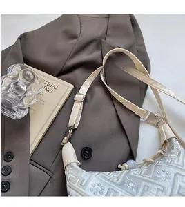 Detail of adjustable silver buckle and textured jacquard fabric on beige dumpling bag