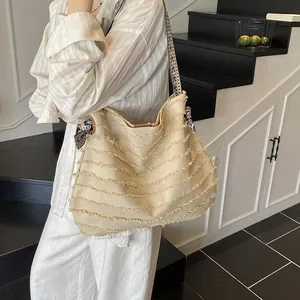 Large straw tote bag with fringe details and geometric strap for summer beach holidays