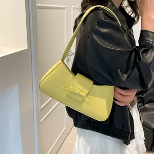 Sac hobo minimaliste jaune citron avec nœud en cuir litchi porté à l'épaule
