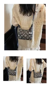 Detail of canvas shoulder bag featuring black and white geometric floral patterns and charm