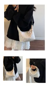 Detail view of white crescent bag with jacquard floral patterns and leather strap