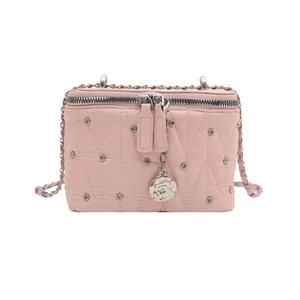 Borsa a tracolla trapuntata rosa con borchie, doppia cerniera e ciondolo a camelia
