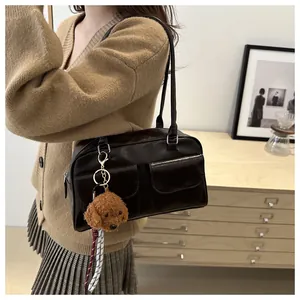 Détail du sac vintage en simili cuir marron foncé avec poches et pendentif ours