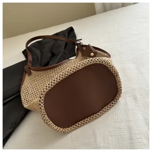 Détail du sac fourre-tout en paille beige avec base en cuir marron et boucle réglable