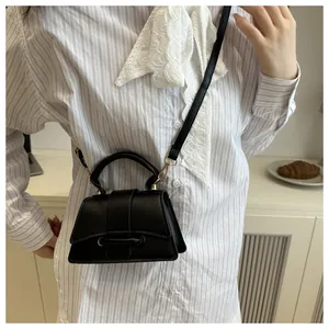Detail view of black trapezoid crossbody bag with metal buckle and detachable strap