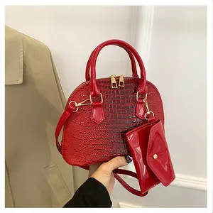 Detail of red crocodile texture shell bag with gold hardware and small pouch