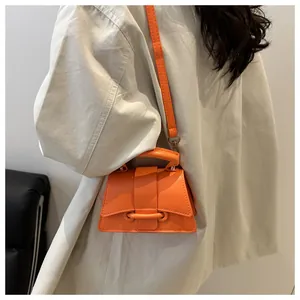 Close-up of vibrant orange mini handbag featuring a unique curved base and structured handle