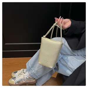 Close-up of golden litchi grain leather crossbody bag with knot strap and logo detail